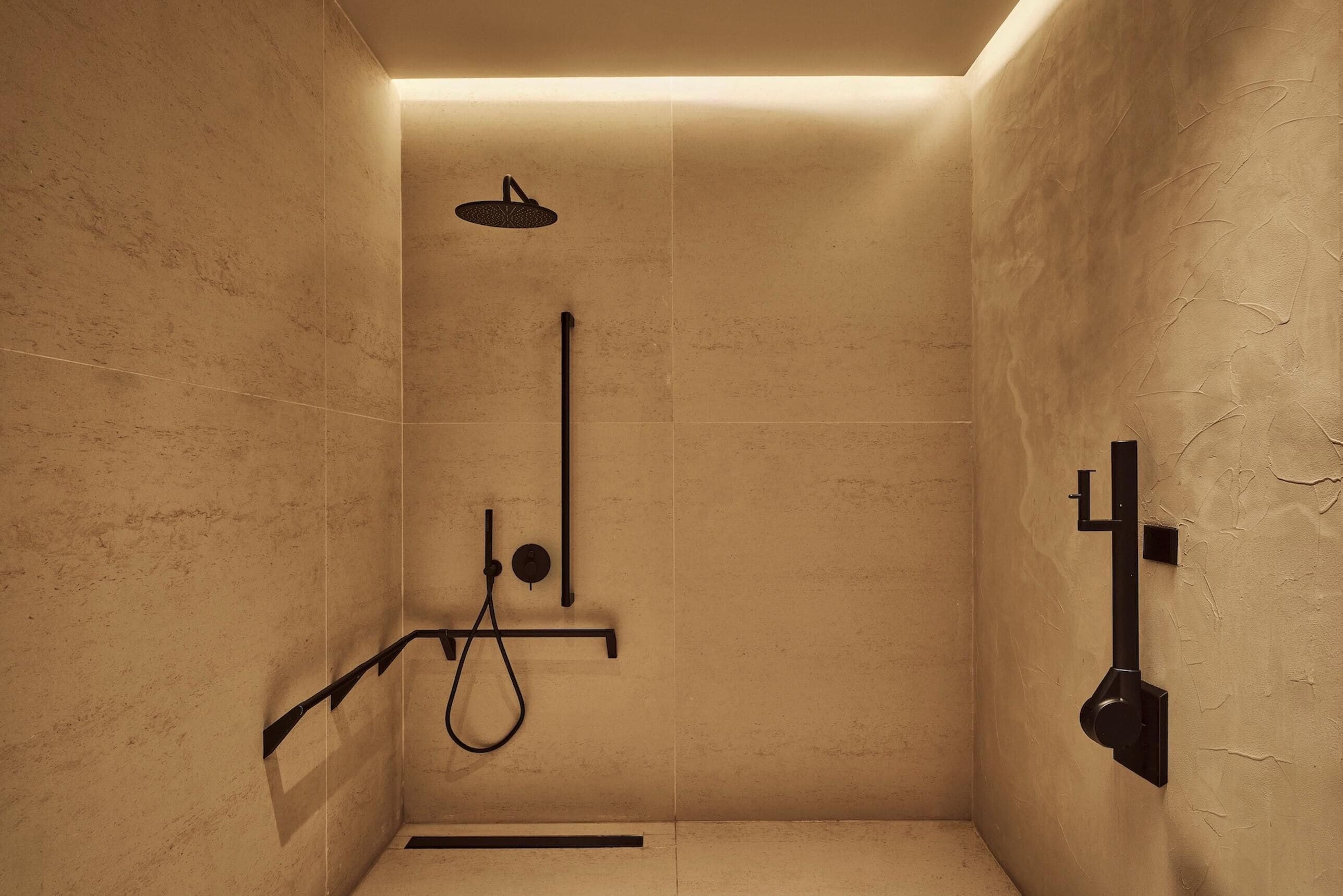 A modern shower with a handheld showerhead, a vertical rain showerhead, and a handheld shower attachment.