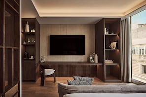 Ein modernes Wohnzimmer mit Flachbildfernseher, Einbauschränken, Essbereich und großem Fenster.