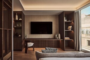 Uma sala de estar moderna com televisão de tela plana, prateleiras embutidas, área de jantar e uma janela grande.