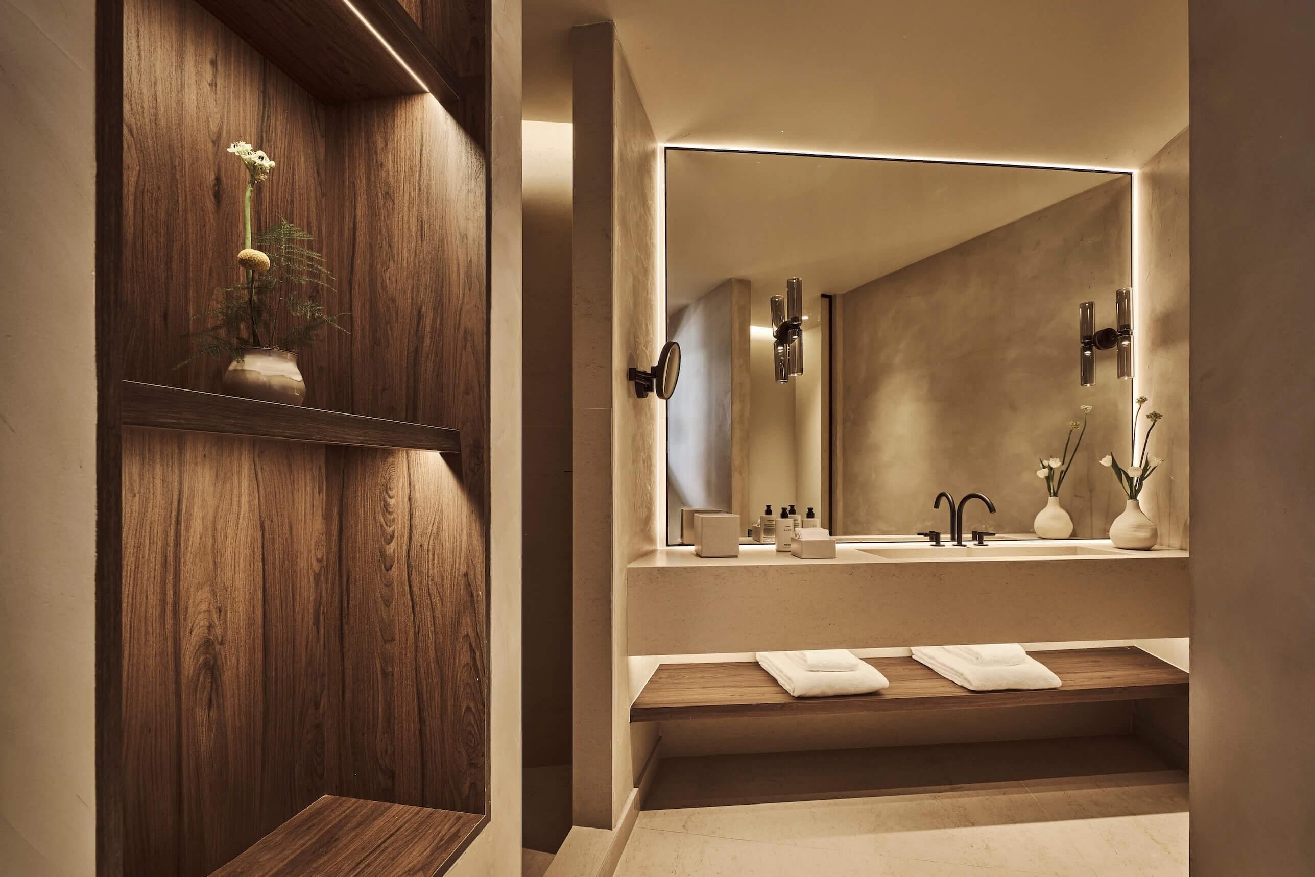 A modern bathroom with a wooden vanity, a large mirror, and a built-in sink.