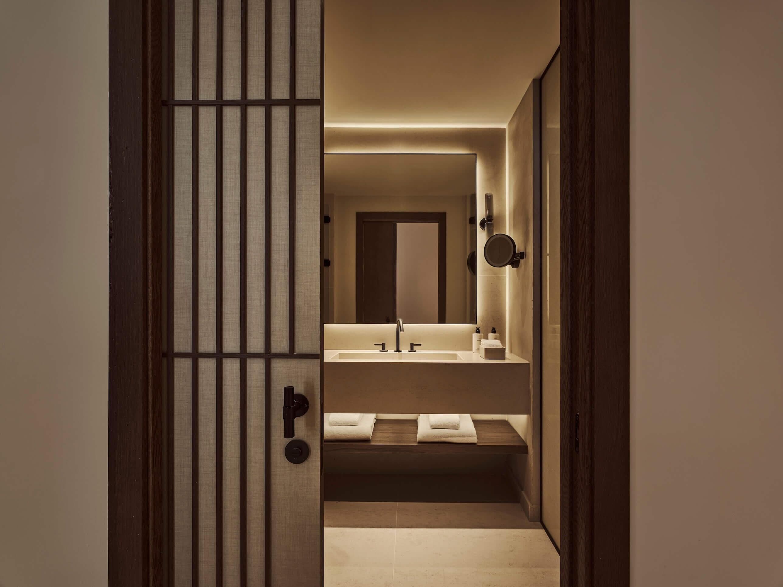 A modern bathroom with a large mirror, two sinks, and a towel rack.