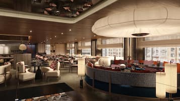 A spacious hotel lobby with a central seating area, multiple tables, and a high ceiling with unique lighting fixtures.