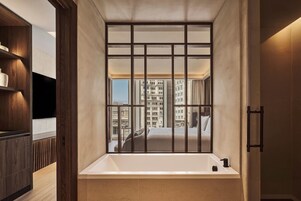 Un baño moderno con bañera, estanterías de madera y vistas a edificios altos.