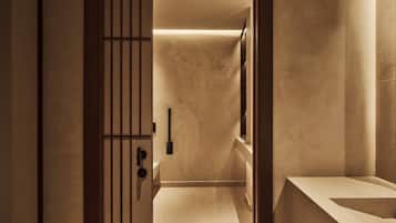 A modern bathroom with a minimalist design, featuring a large mirror, a sink, and a door with vertical bars.