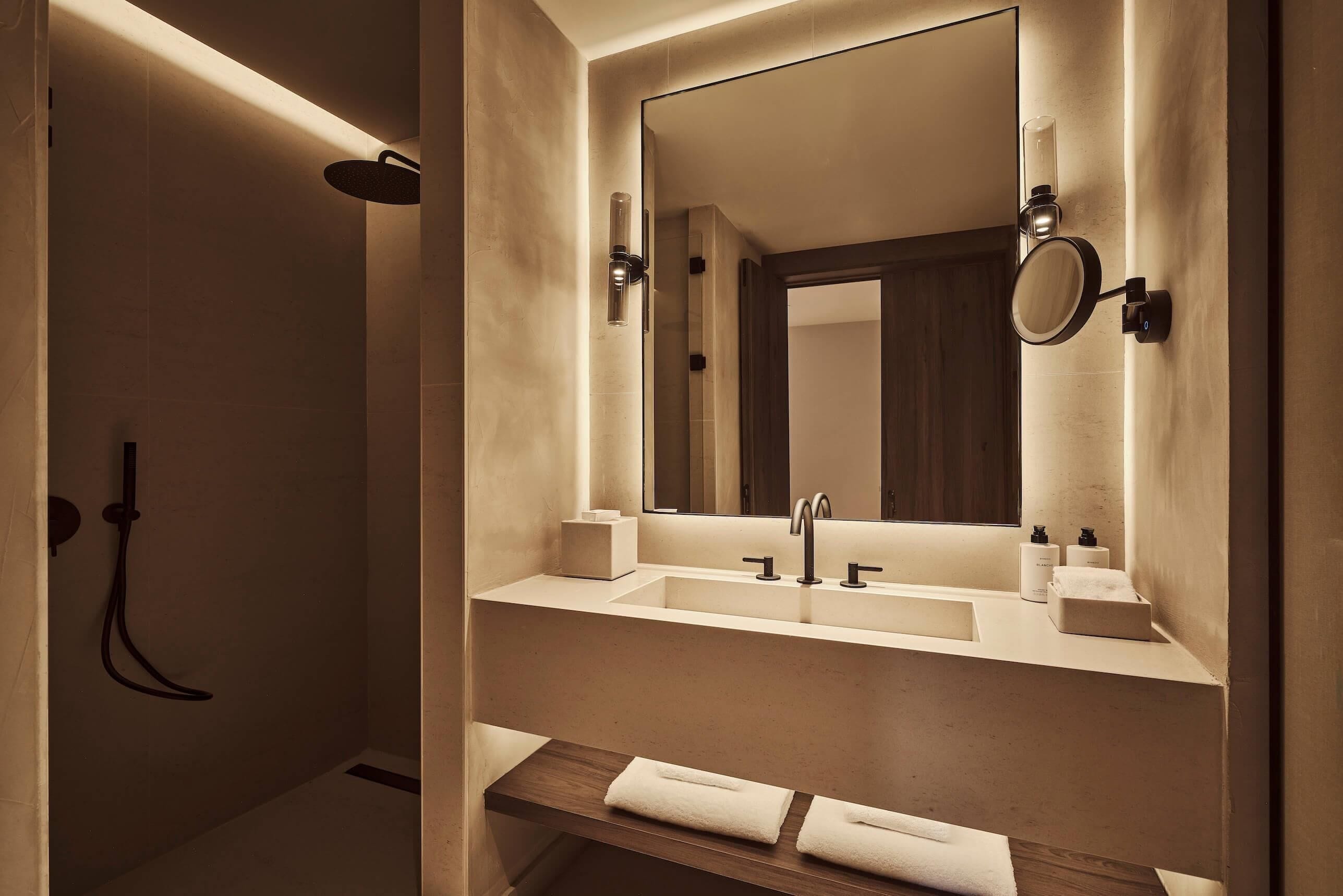 A modern bathroom with a walk-in shower, a large mirror, and a vanity with a sink and towel rack.