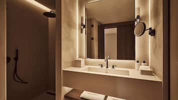 A modern bathroom with a walk-in shower, a large mirror, and a vanity with a sink and towel rack.