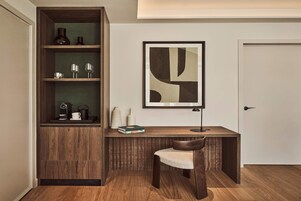 Quarto moderno com escrivaninha de madeira, uma cadeira, estante e uma obra de arte abstrata emoldurada na parede.