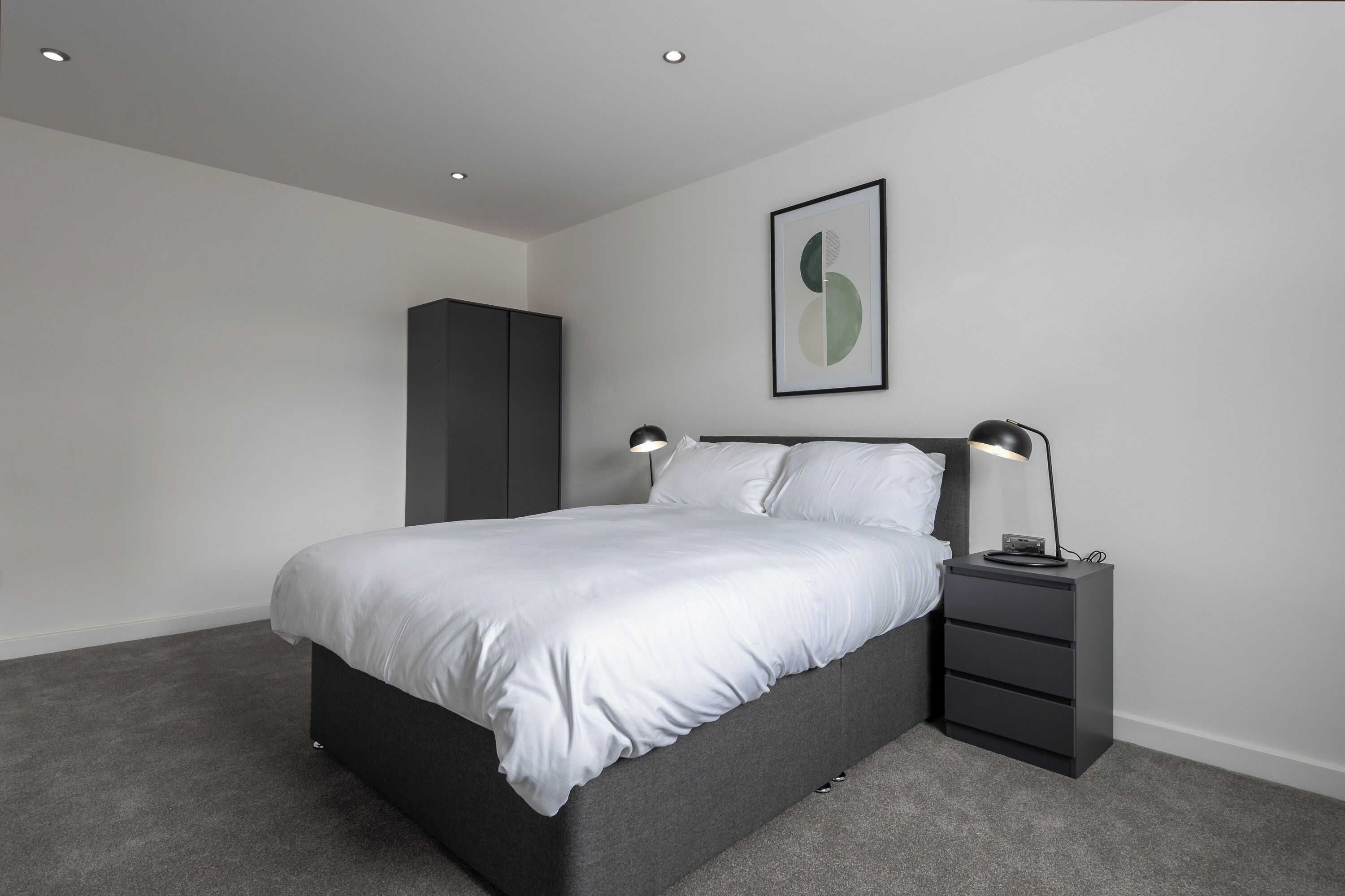 A modern bedroom with a bed, bedside tables, a wardrobe, and a framed artwork on the wall.