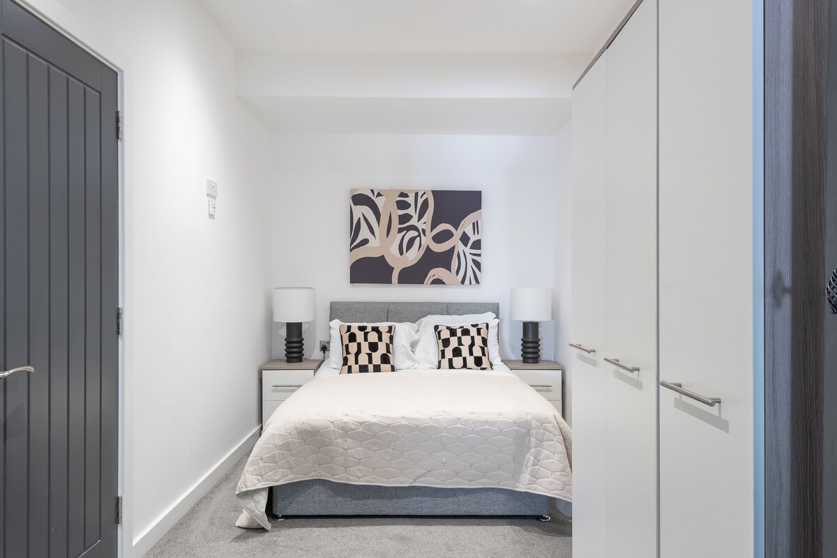 A bedroom with a bed, bedside tables, a wall-mounted artwork, and a wardrobe.