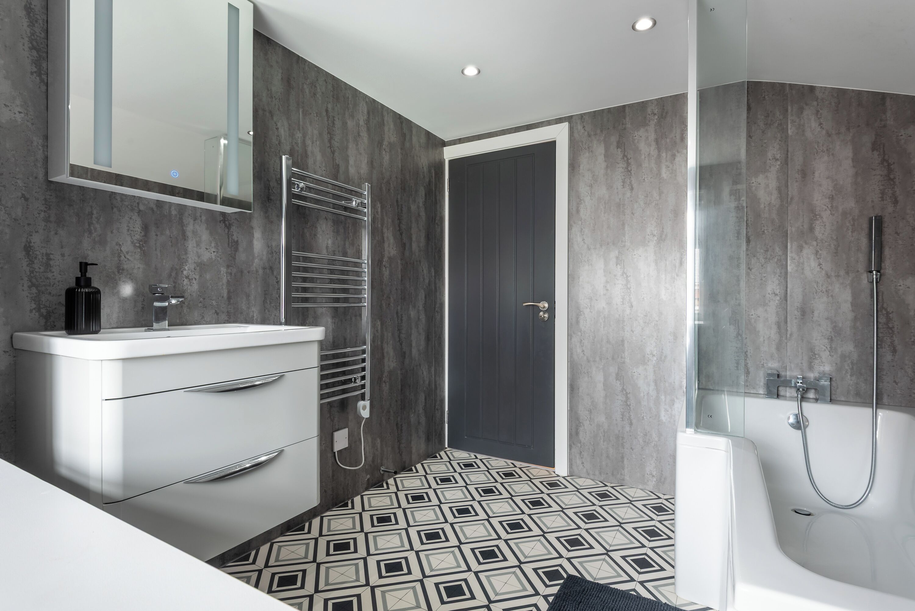Une salle de bain moderne avec un meuble-lavabo blanc, une cabine de douche en verre et un carrelage décoratif.