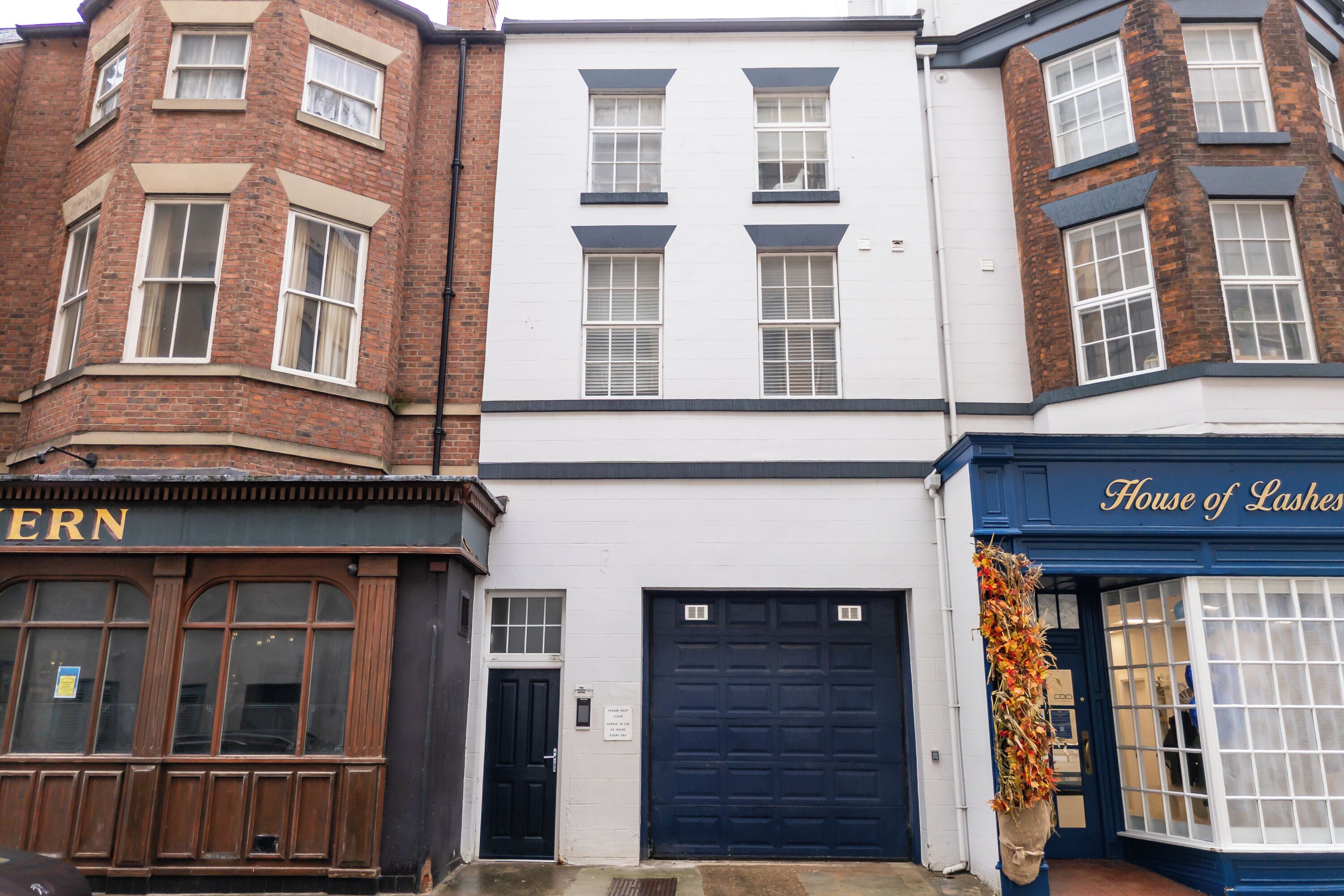 A corner building with a black door, a blue garage door, and a sign reading 'House of Lashes.'