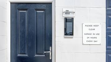 A dark blue door with a metal handle and a sign stating 'PLEASE KEEP CLEAR GARAGE IN USE 24 HOURS EVERY DAY.'