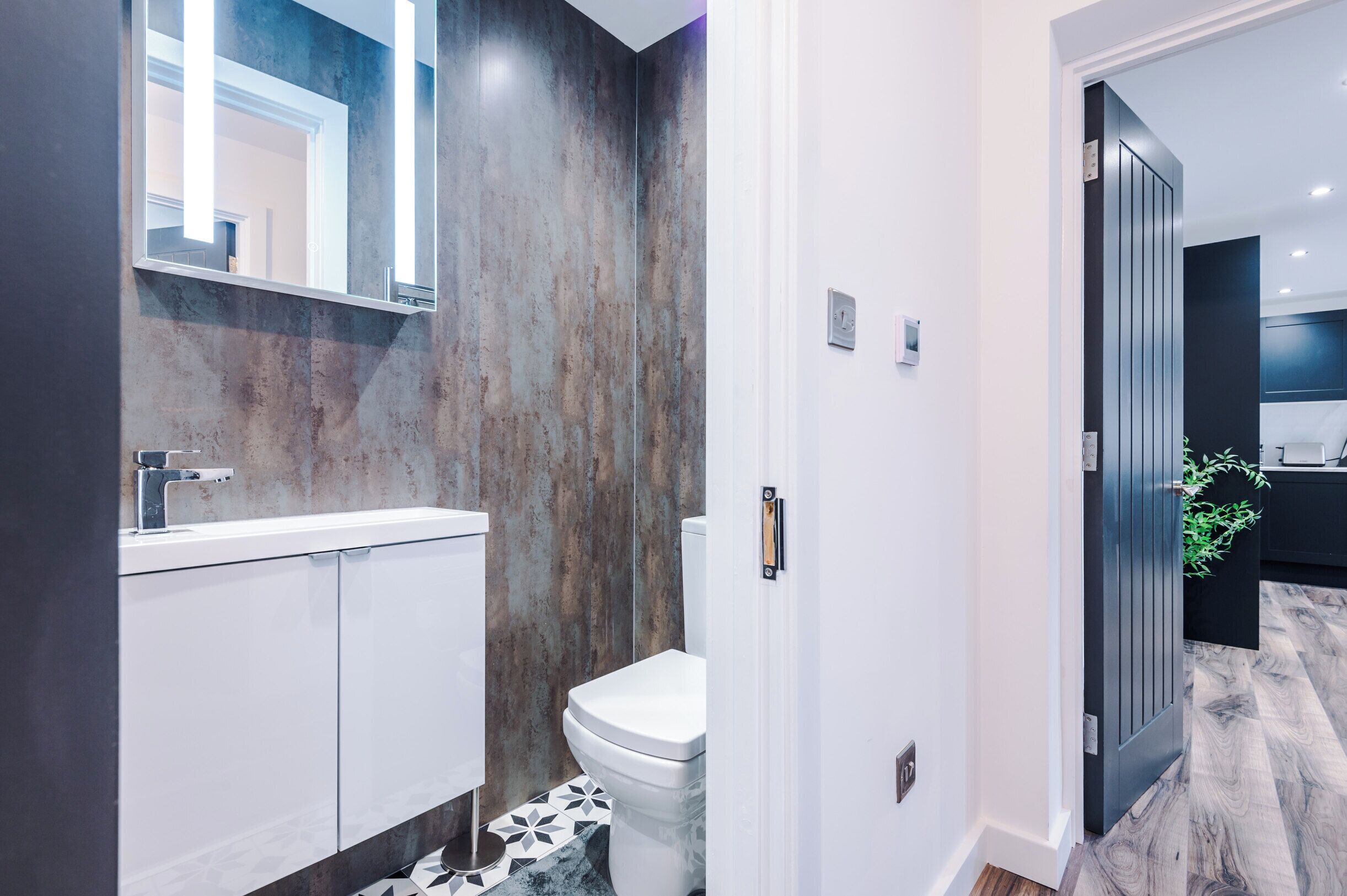 Un baño moderno con inodoro blanco, un espejo grande y un tocador blanco.
