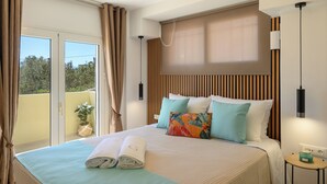 Habitación de hotel con cama, almohadas, mesita de noche, lámpara y vistas al exterior.