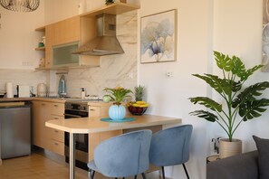 Eine moderne Küche mit Marmor-Spritzschutz, Edelstahlgeräten und einer blauen Vase mit Blumen.