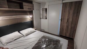 Un dormitorio con cama, armario y espejo.