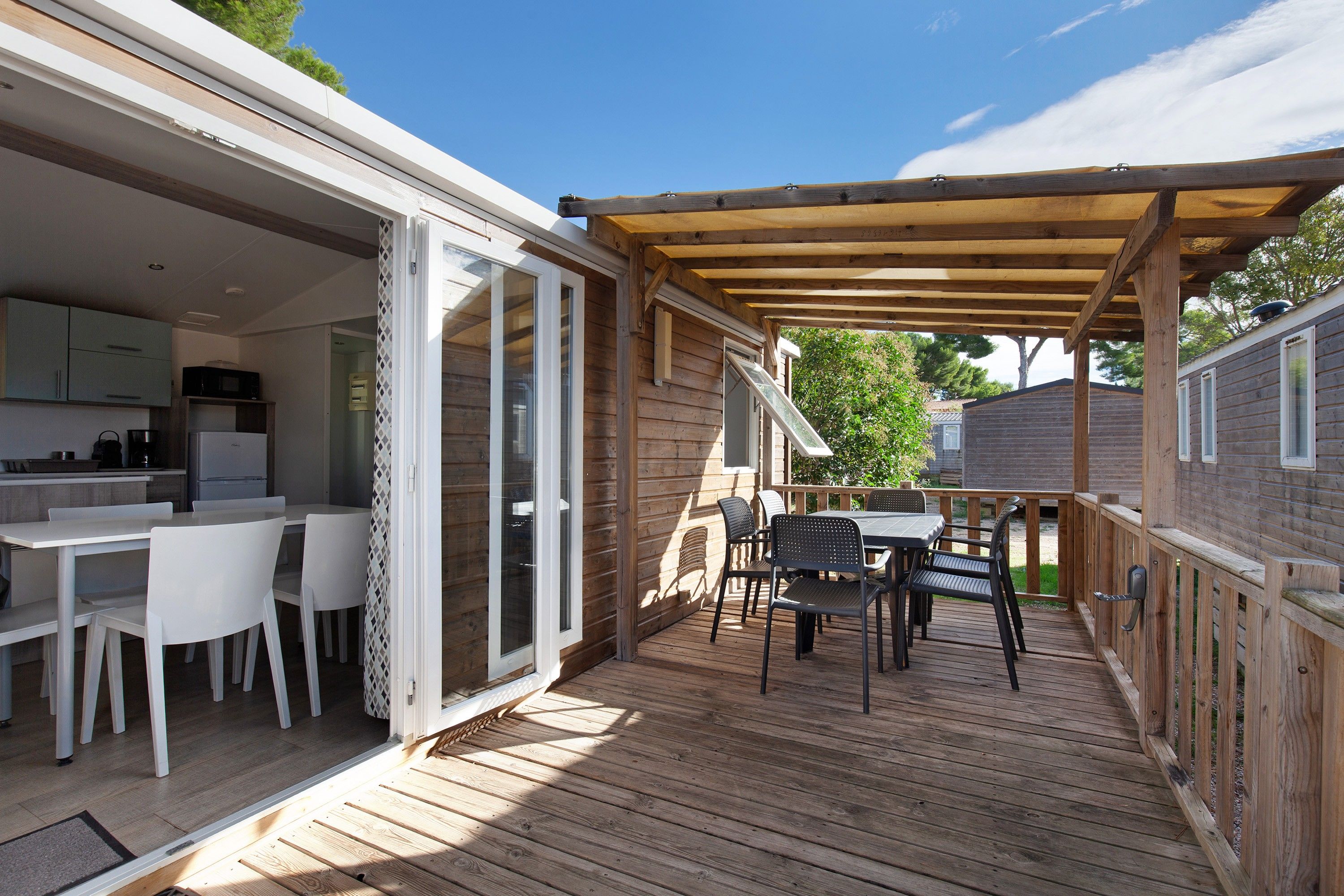 A wooden deck with a dining area and a kitchen.
