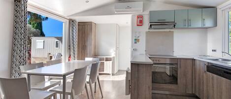 A modern kitchen with a built-in oven and dishwasher, wooden cabinets, and a dining area with a table and chairs.