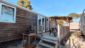 Una cabaña de madera con un porche, estufa a gas y un espacio de estar cubierto.