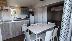 Una cocina compacta con comedor, armarios blancos y un microondas integrado.