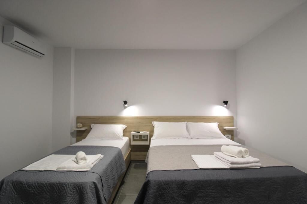 Ein Hotelzimmer mit zwei Einzelbetten, einem Holzkopfteil, Nachttischen und einer Wand-Klimaanlage.