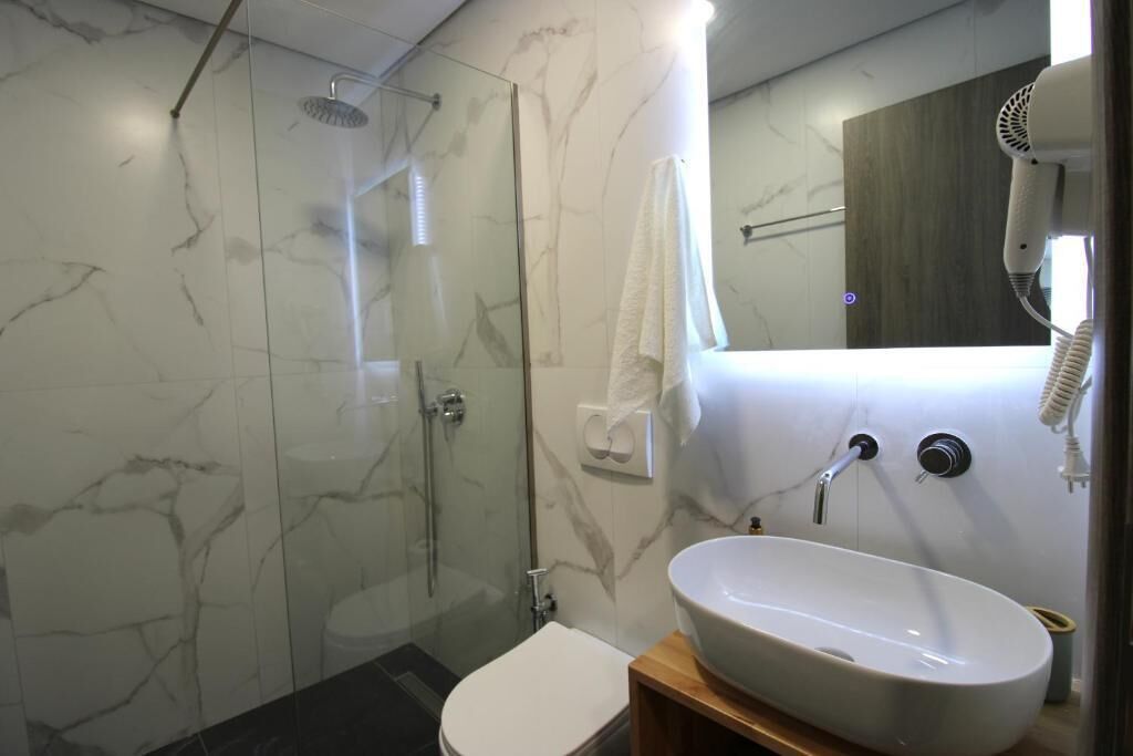 A bathroom with a glass-enclosed shower, a white sink, and a mirror.