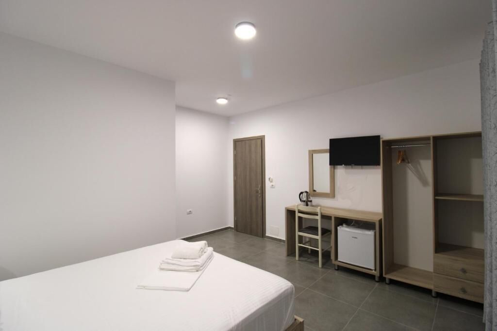 A bedroom with a bed, a desk, a wardrobe, and a mirror.