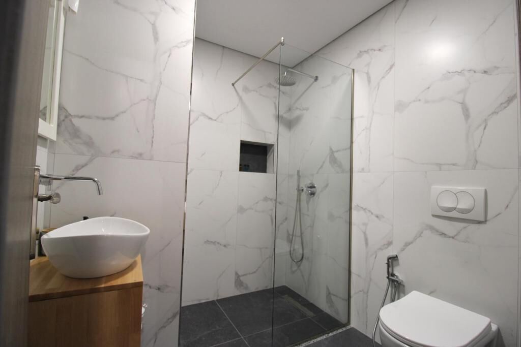 A bathroom with a white sink, a shower, and a toilet.