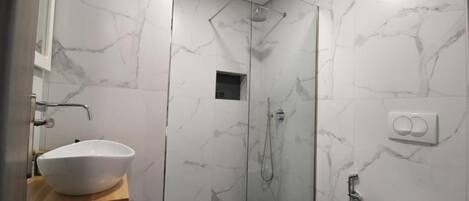 A bathroom with a white sink, a shower, and a toilet.