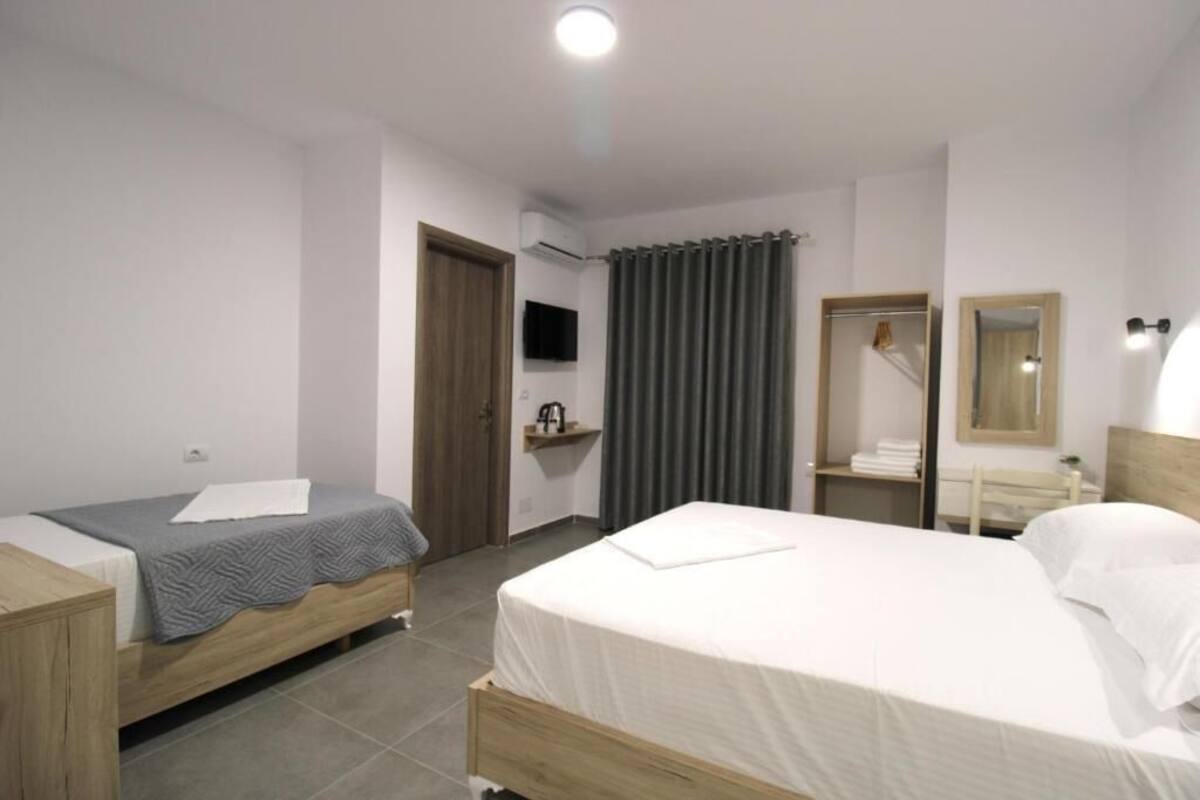 A bedroom with two beds, a wardrobe, a mirror, and a TV.