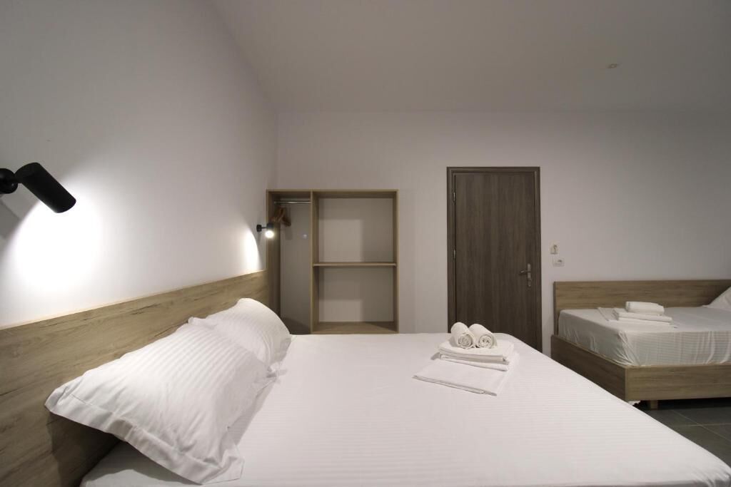 Una habitación de hotel con una cama grande, un armario y una pequeña estantería.