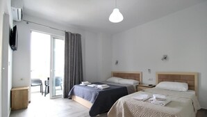 Habitación de hotel con dos camas, televisión, lámpara de techo y puerta corrediza de vidrio que da a un espacio al aire libre.
