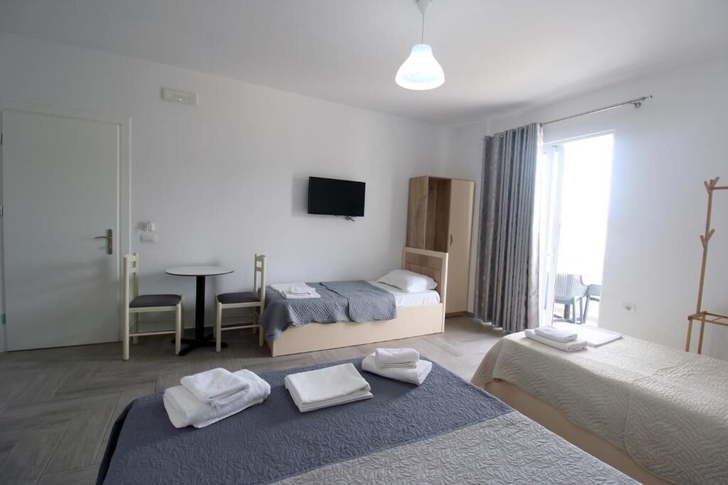 Hotellihuone, jossa on sänky, televisio, pieni pöytä ja tuoli.