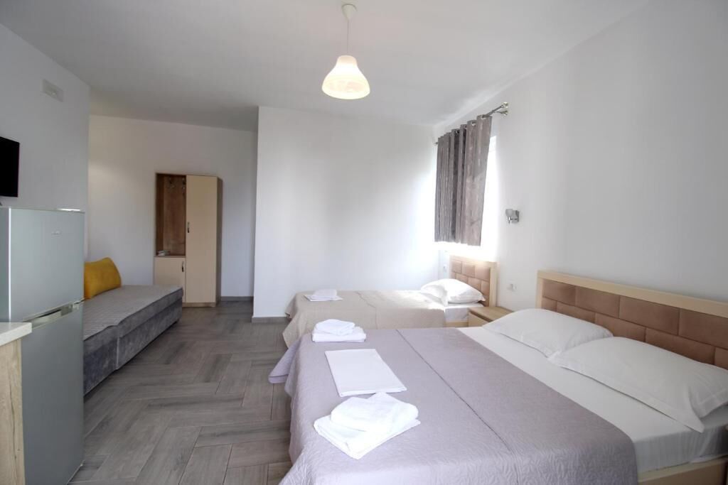 Habitación de hotel con dos camas, un sofá, televisión y kitchenette.