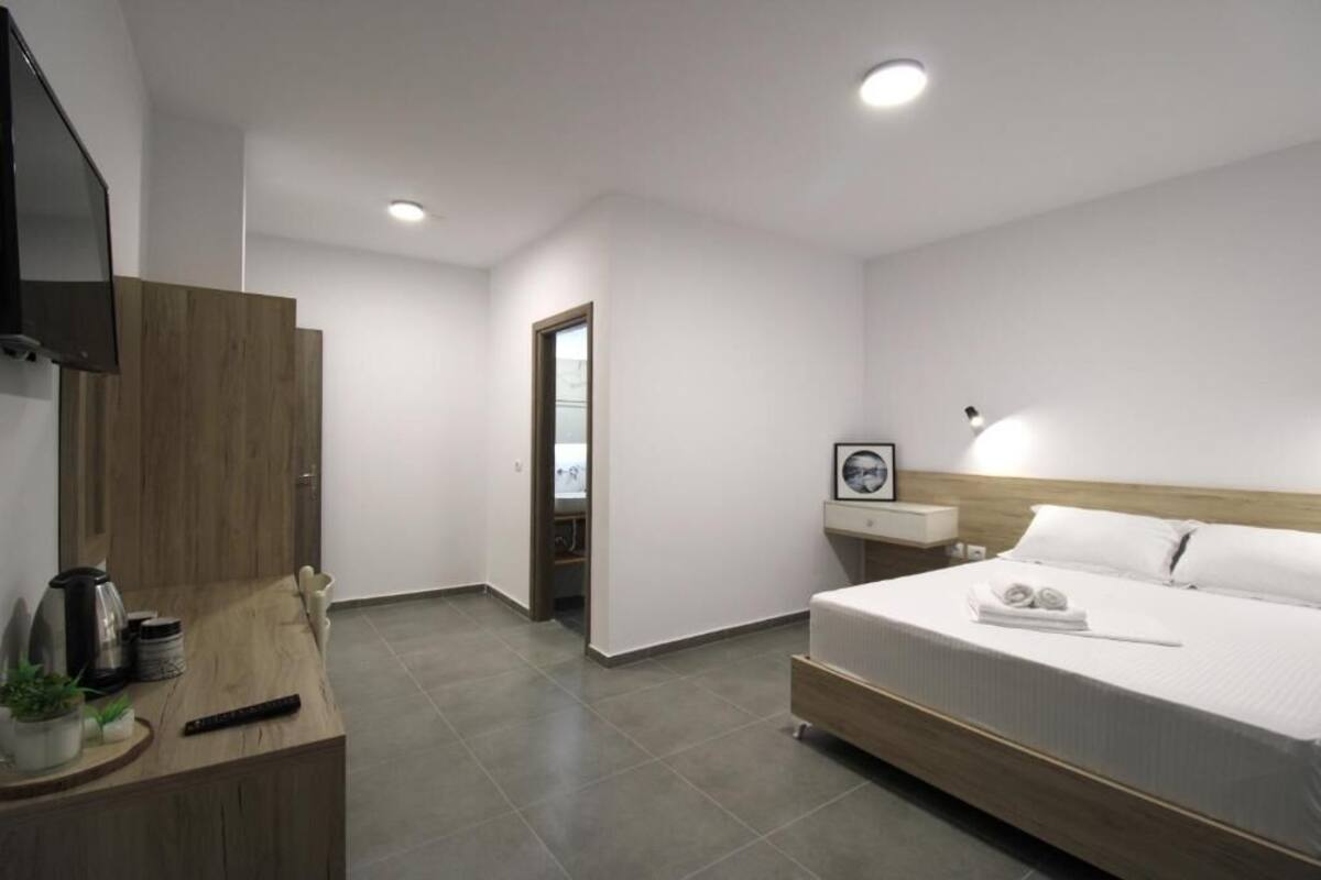 A modern hotel room with a bed, bedside table, and a TV mounted on the wall.
