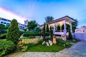 A garden with a gazebo, stone pathway, and a statue. - Helena Park Hotel (Nessebar)