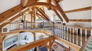 Ein geräumiger Innenraum mit Holzbalken, einem Balkon und einem Essbereich.