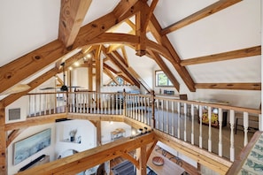 Ein geräumiger Innenraum mit Holzbalken, einem Balkon und einem Essbereich.
