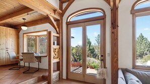 Ein Holzinnenraum mit Essbereich, einer Couch und einem großen Schiebeglasfenster, das auf eine Terrassenfläche im Freien führt.