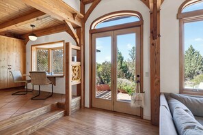 Ein Holzinnenraum mit Essbereich, einer Couch und einem großen Schiebeglasfenster, das auf eine Terrassenfläche im Freien führt.