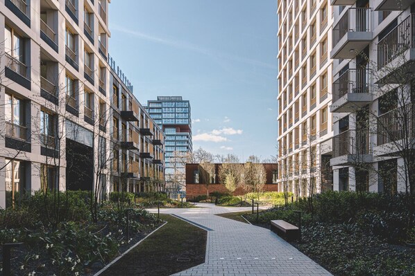 A modern urban residential area with multi-story buildings, a central pathway, and greenery. - Estilo | Designerski Apartament z Tarasem (Bydgoszcz)