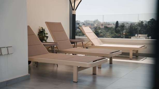 Zona relax moderna con poltrone reclinabili e un tavolino, ampie finestre con vista sulla città.