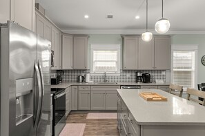Une cuisine moderne dotée d’appareils électroménagers en acier inoxydable, de meubles de couleur claire et d’un îlot central.