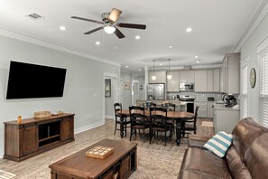 Ein modernes Wohnzimmer mit Essbereich, Küche und Deckenventilator.