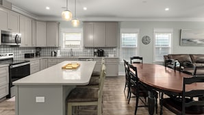 Una cocina moderna con una isla central, mesa de comedor y sillas, rodeada de armarios y electrodomésticos.