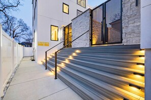 Ein modernes Gebäude mit einer Treppe, einem Schild mit der Aufschrift 'SUNRISE' und einem Weg zum Eingang.