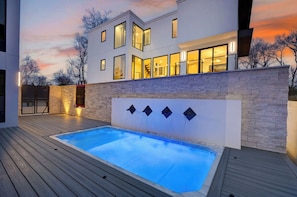 Ein modernes Haus mit Swimmingpool, Steinmauer und großen Fenstern.