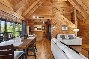 Ein Holzblockhaus-Interieur mit Essbereich, Sofa und Küche.