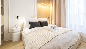 Ein modernes Hotelzimmer mit einem großen Bett, Nachttischen, einem Holzkopfende und Blick auf die Stadt durch transparente Vorhänge.
