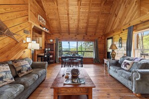 Ein Holzhütten-Interieur mit Essbereich, zwei Sofas und einem Tisch mit einer Schüssel.